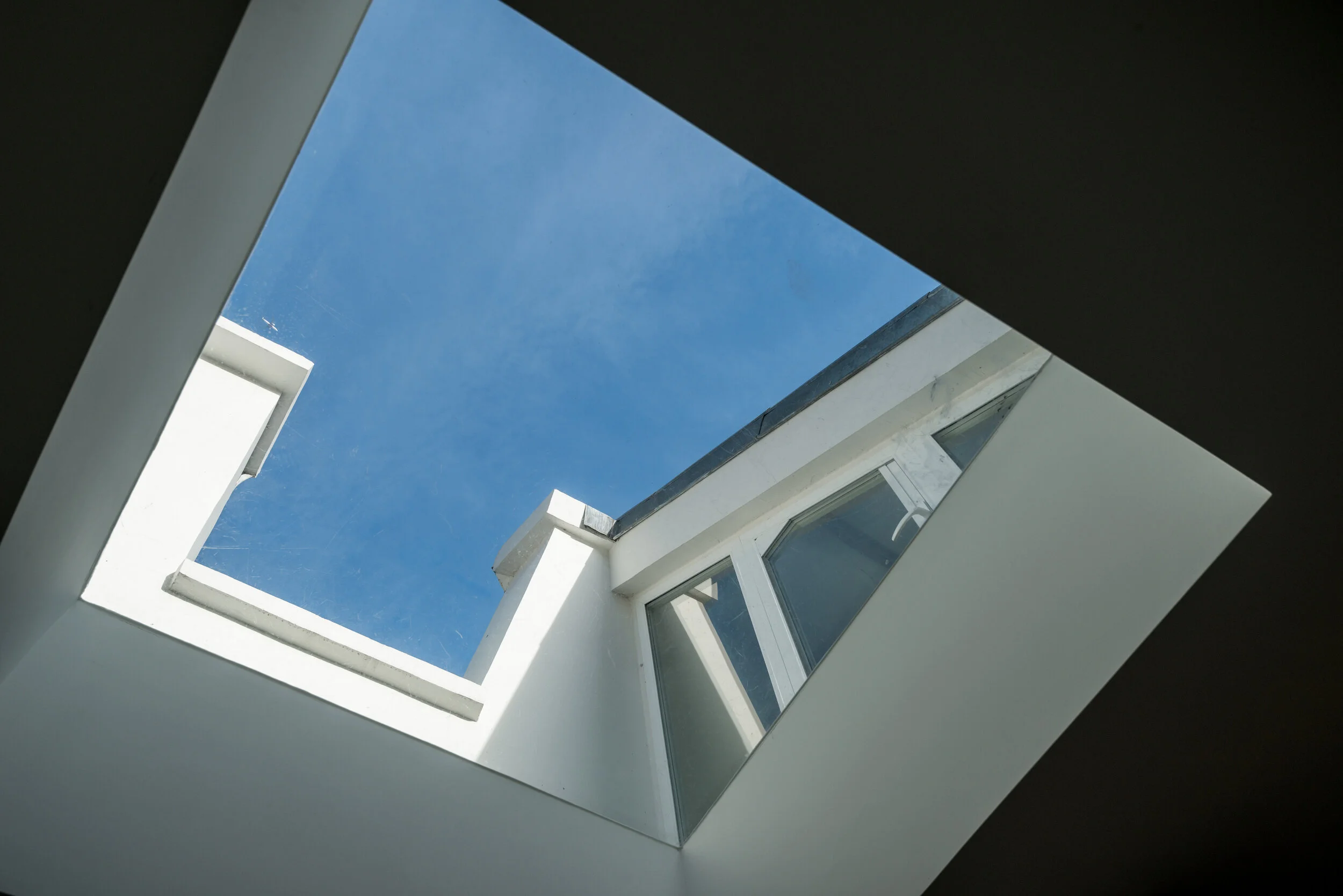 Skylight framing blue sky above a dark sloped ceiling