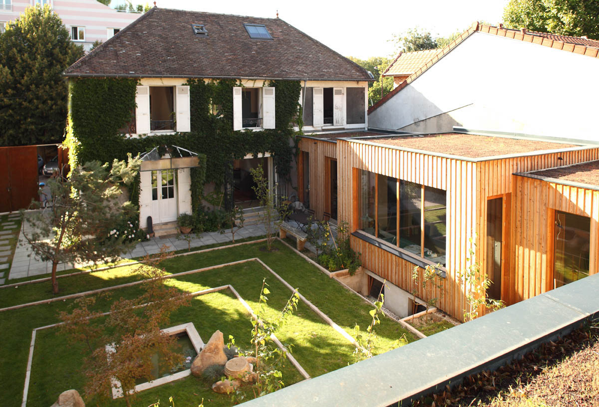 Aerial view of the timber studio with planted roof beside the old ivy-covered house