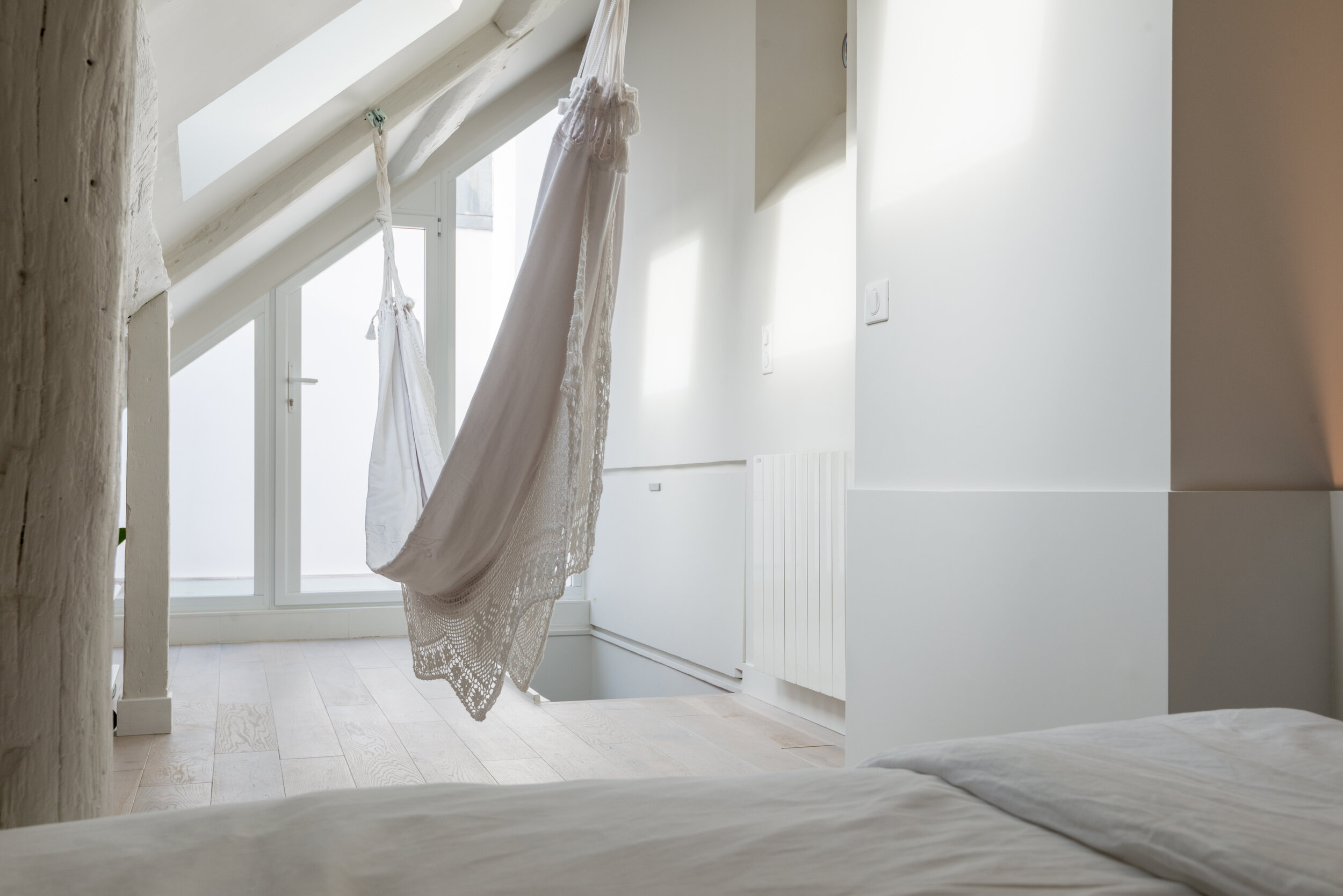 Attic room under sloped windows with a hammock and low bed