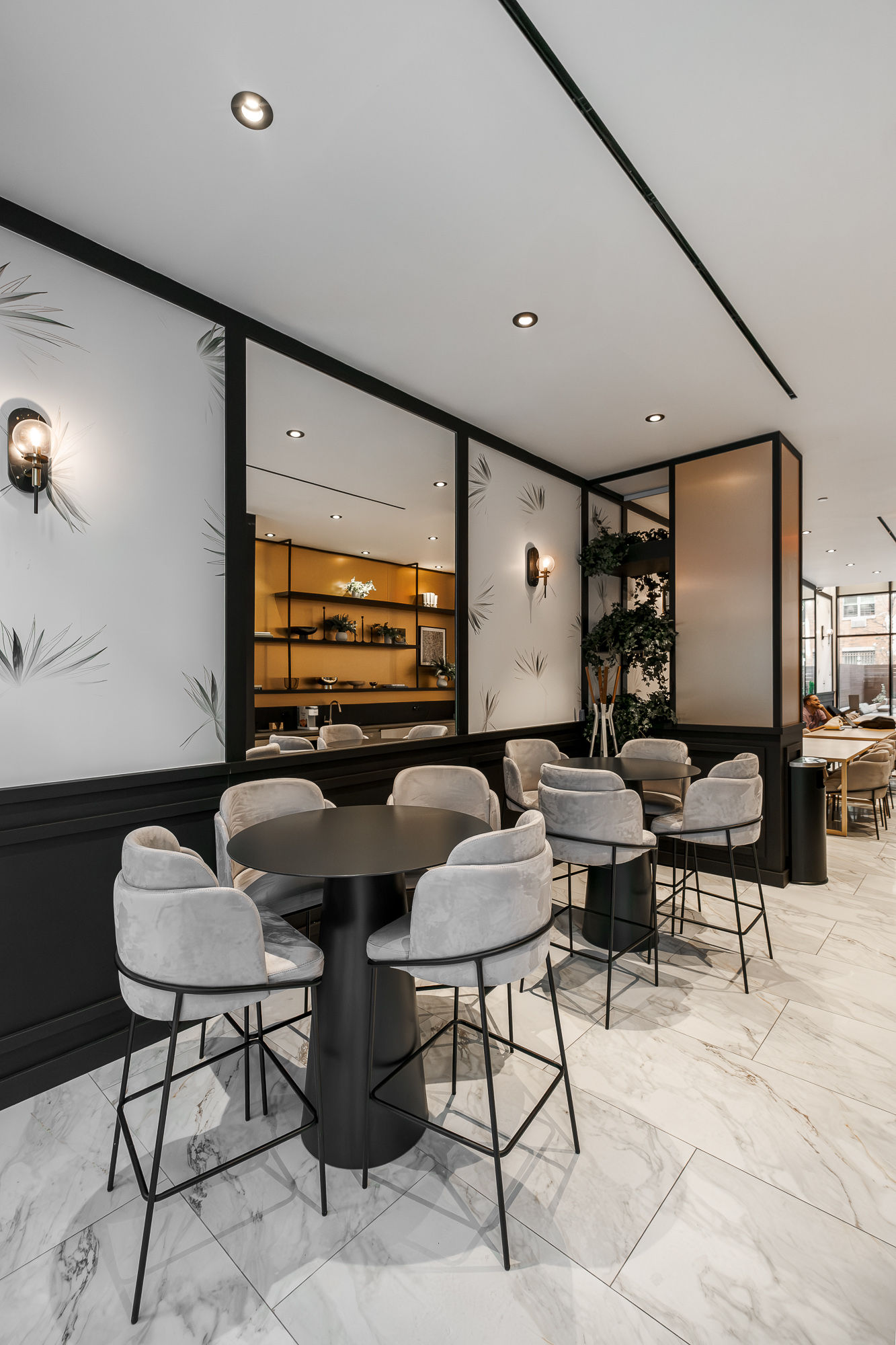 Café and social corner with black bistro tables and etched glass partitions