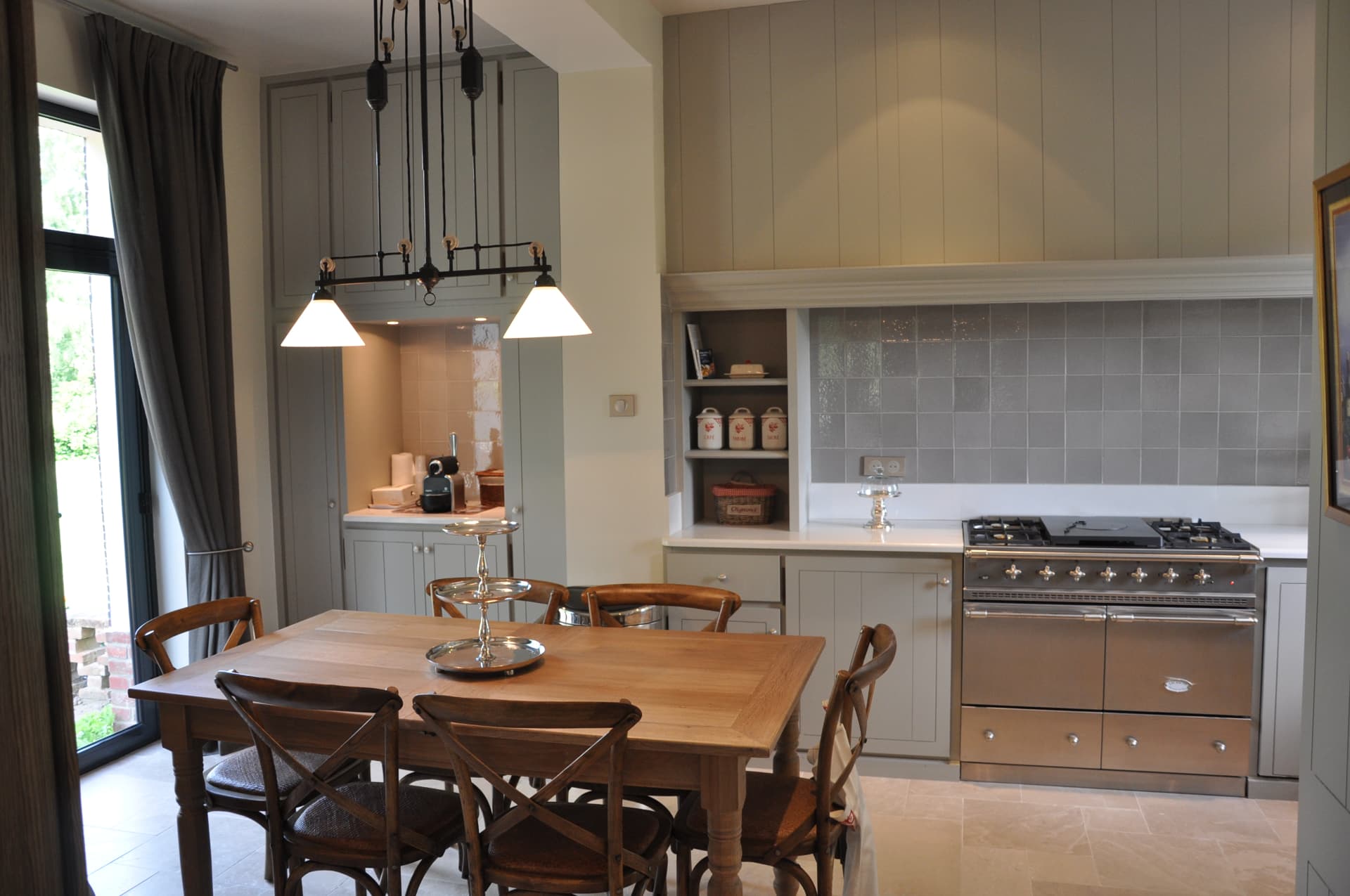 Kitchen dining table with oak chairs, range cooker and glazed grey tiled splashback