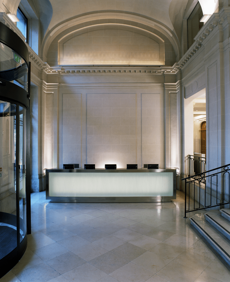Air Liquide head office reception hall with stone walls, barrel vault ceiling and illuminated concierge desk