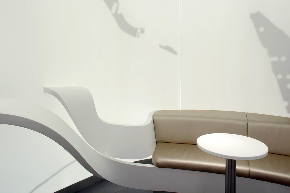Sculptural white bench flowing into a leather banquette with a side table