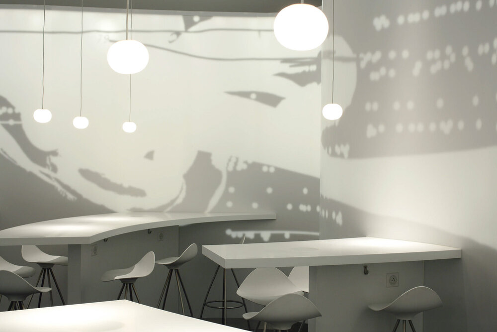 High tables and pendant globes against the printed glass mural of an aircraft