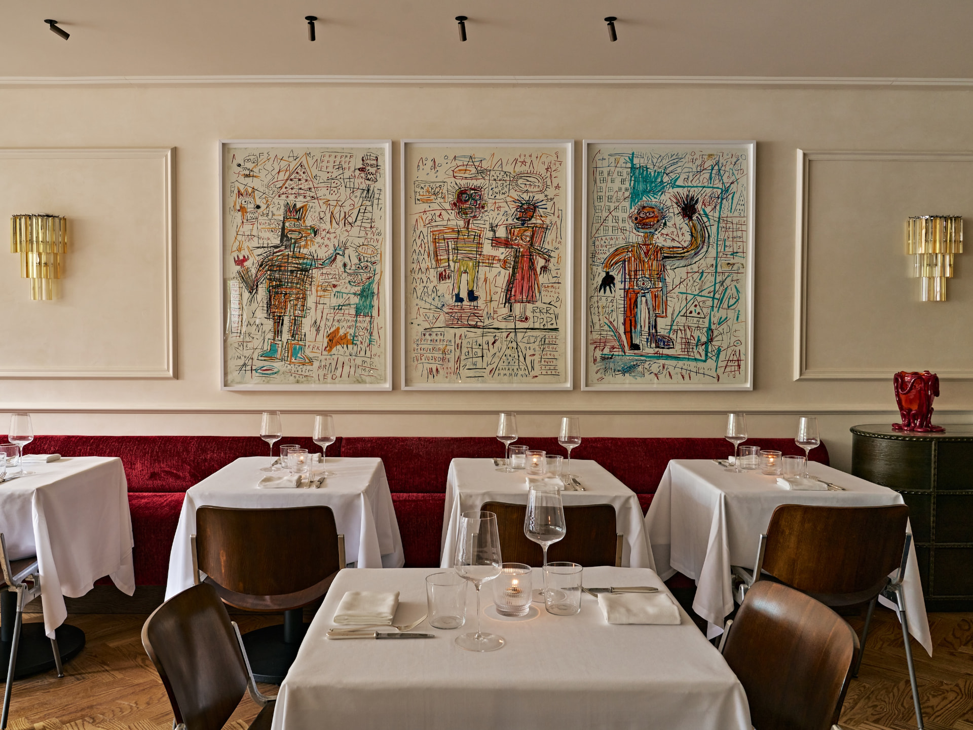 Le Chêne dining room — red velvet banquettes, white tablecloths and triptych artwork