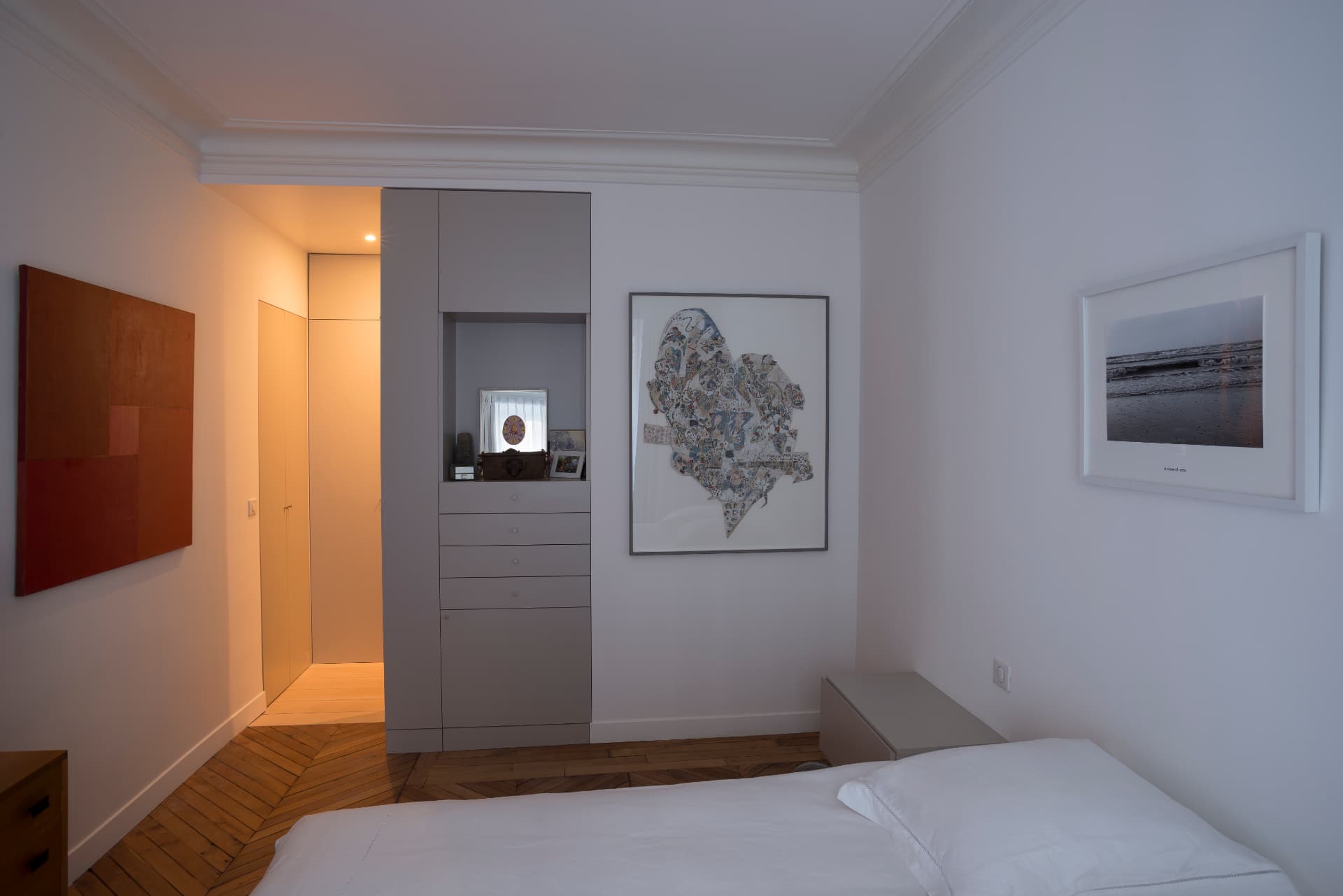 Bedroom with bespoke wardrobe wall, contemporary artworks and chevron parquet