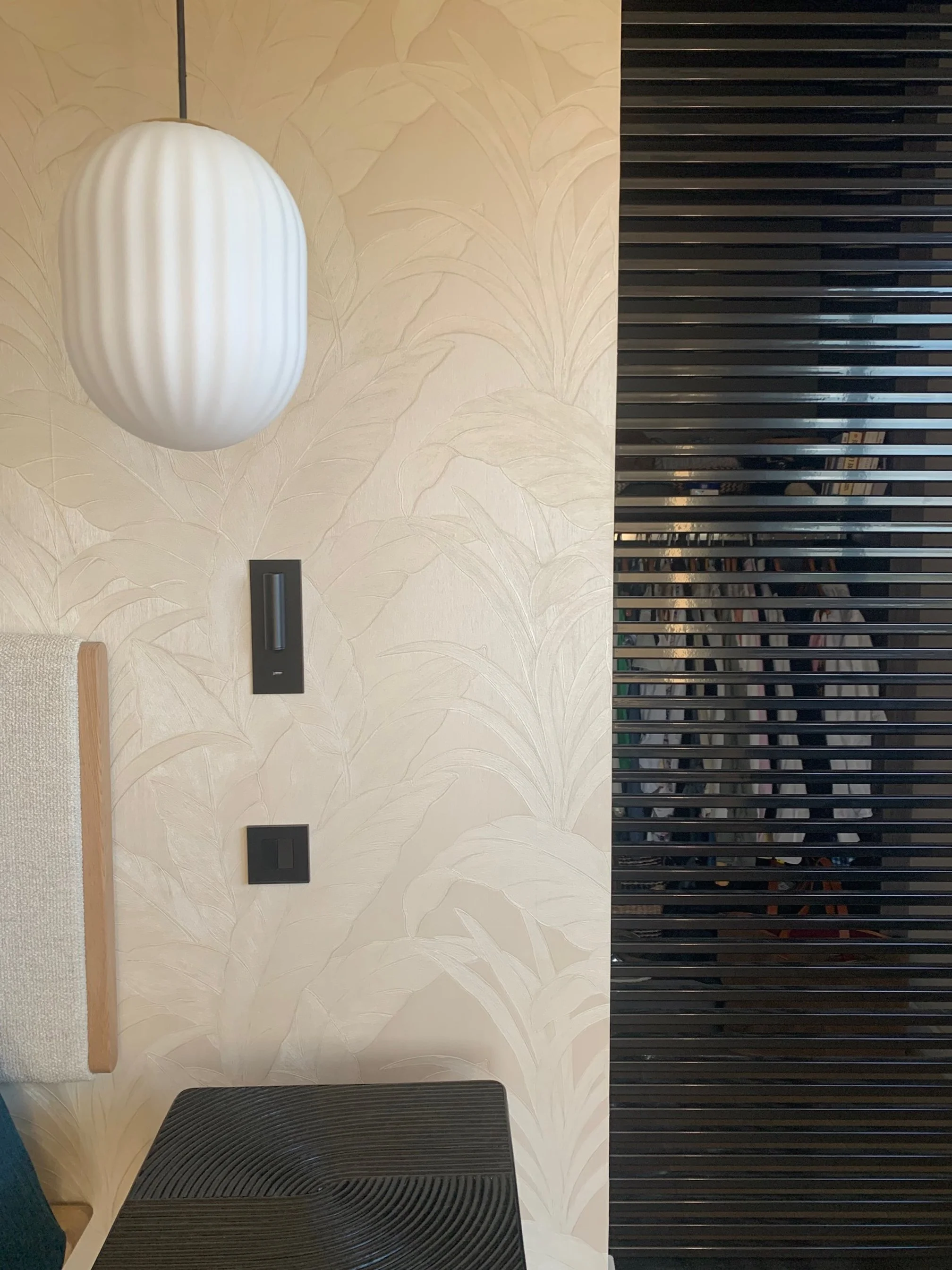 Hand-plastered wall with an opaline pendant beside a slatted timber screen