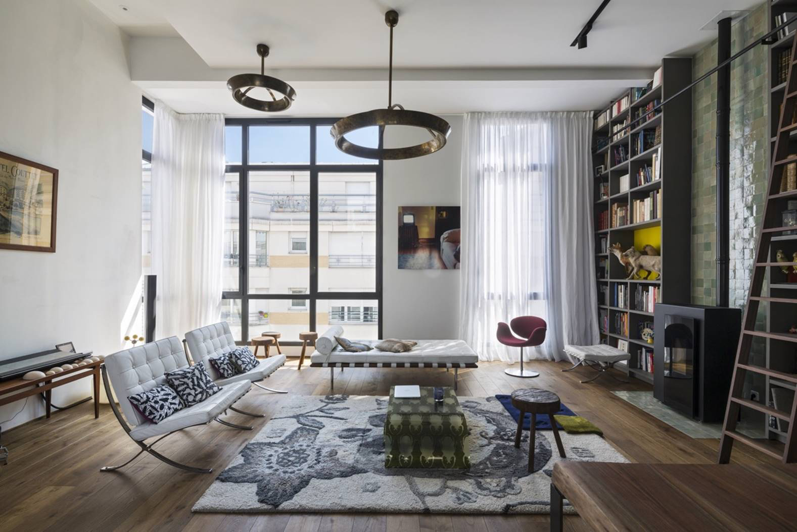 Cathedral-height living room with double-height glazing, brass ring pendants and bespoke shelving