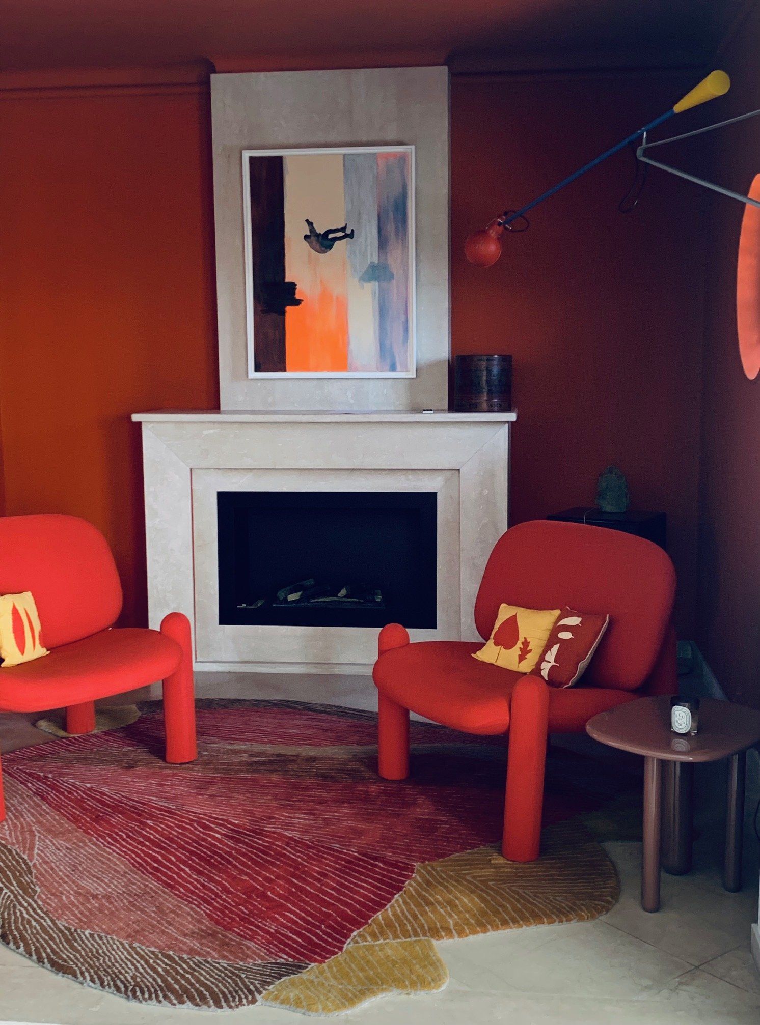 Salon with terracotta walls, stone fireplace and red armchairs