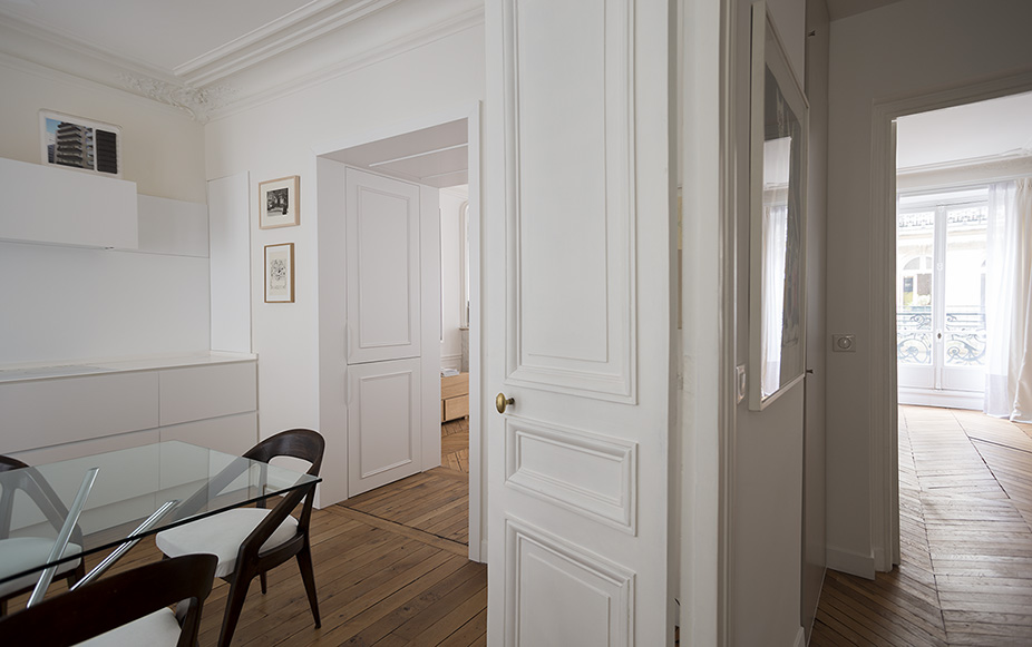 Dining area with glass table and panelled doors opening to the hallway