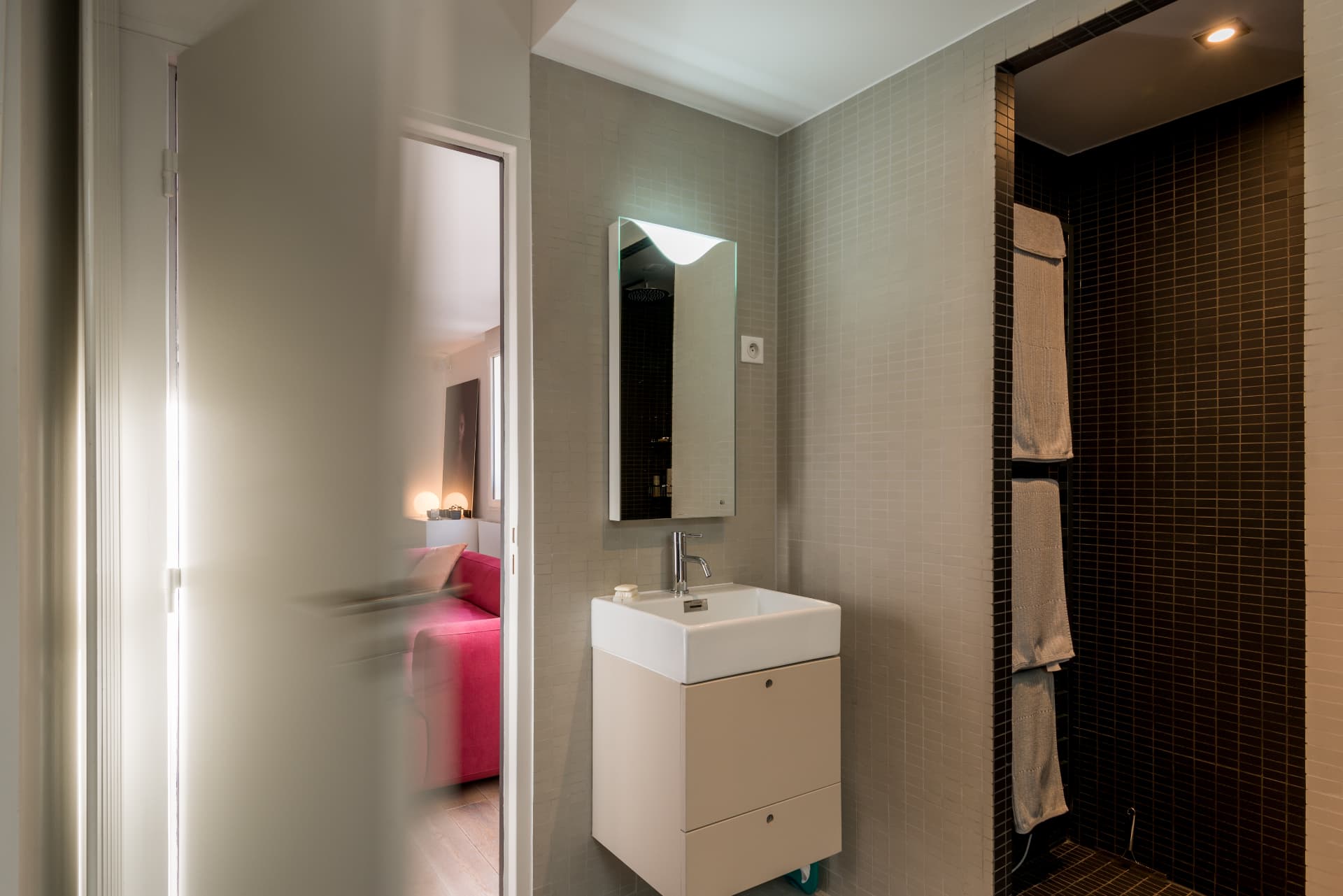 Bathroom with a floating sink, mirror and dark mosaic shower