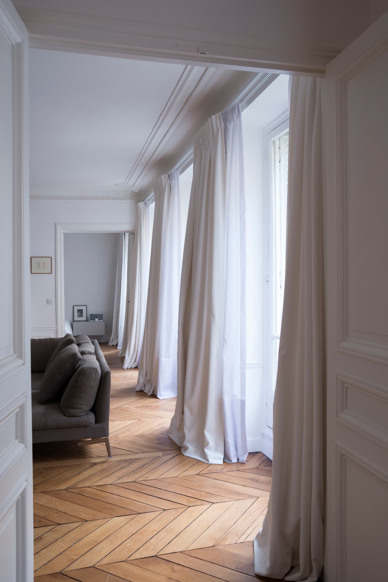 Enfilade of rooms with full-height curtains along tall Parisian windows