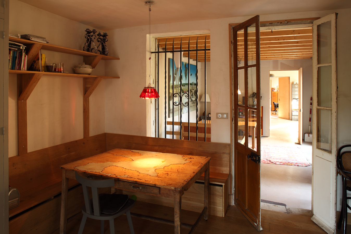 Dining nook with timber banquette, shelves and red glass pendant
