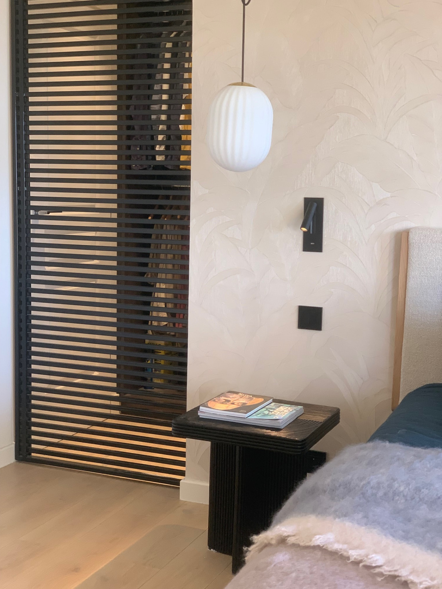 Bedroom detail with slatted wardrobe, ribbed pendant and palm wallpaper