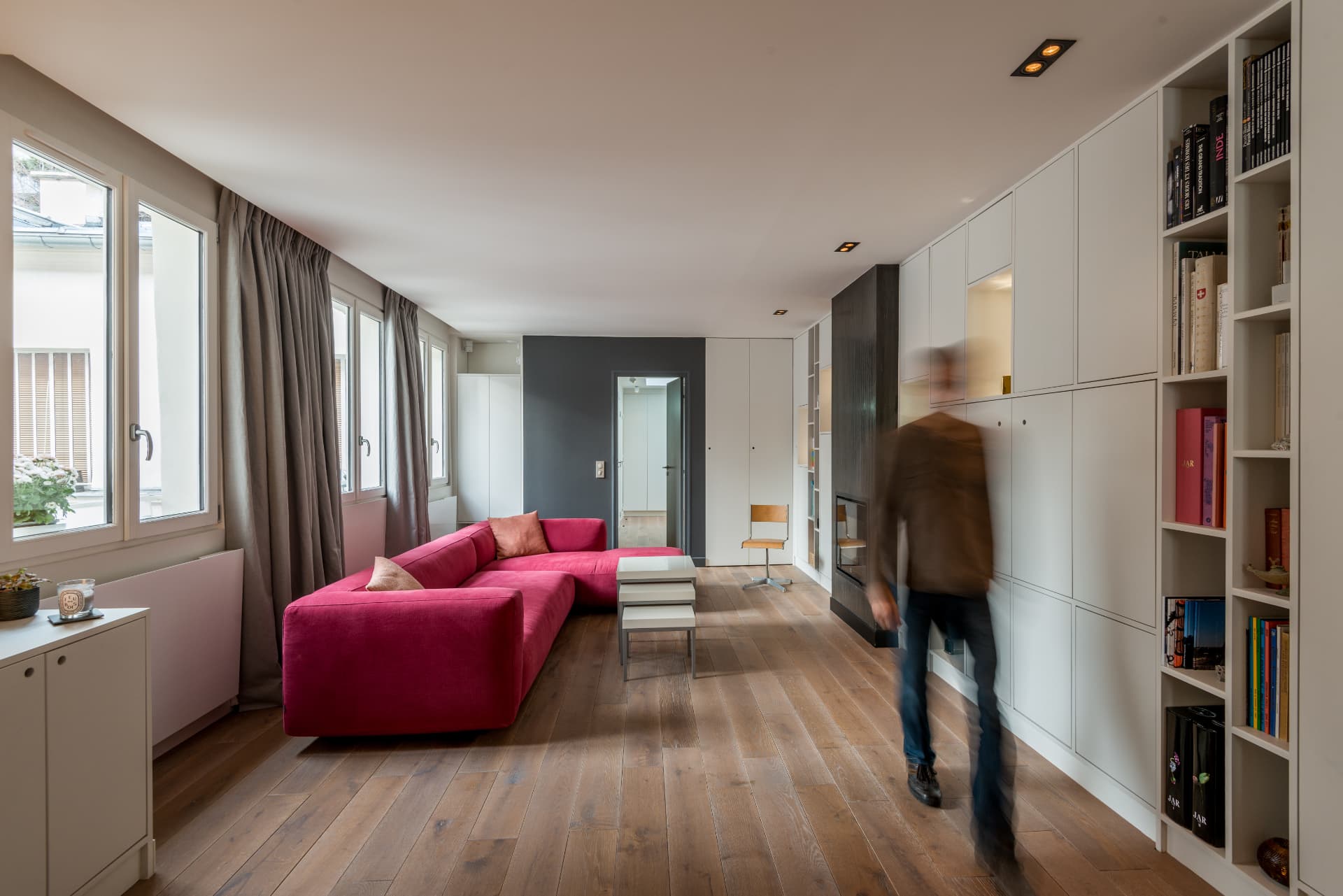 Living room with a raspberry sofa and full-height joinery