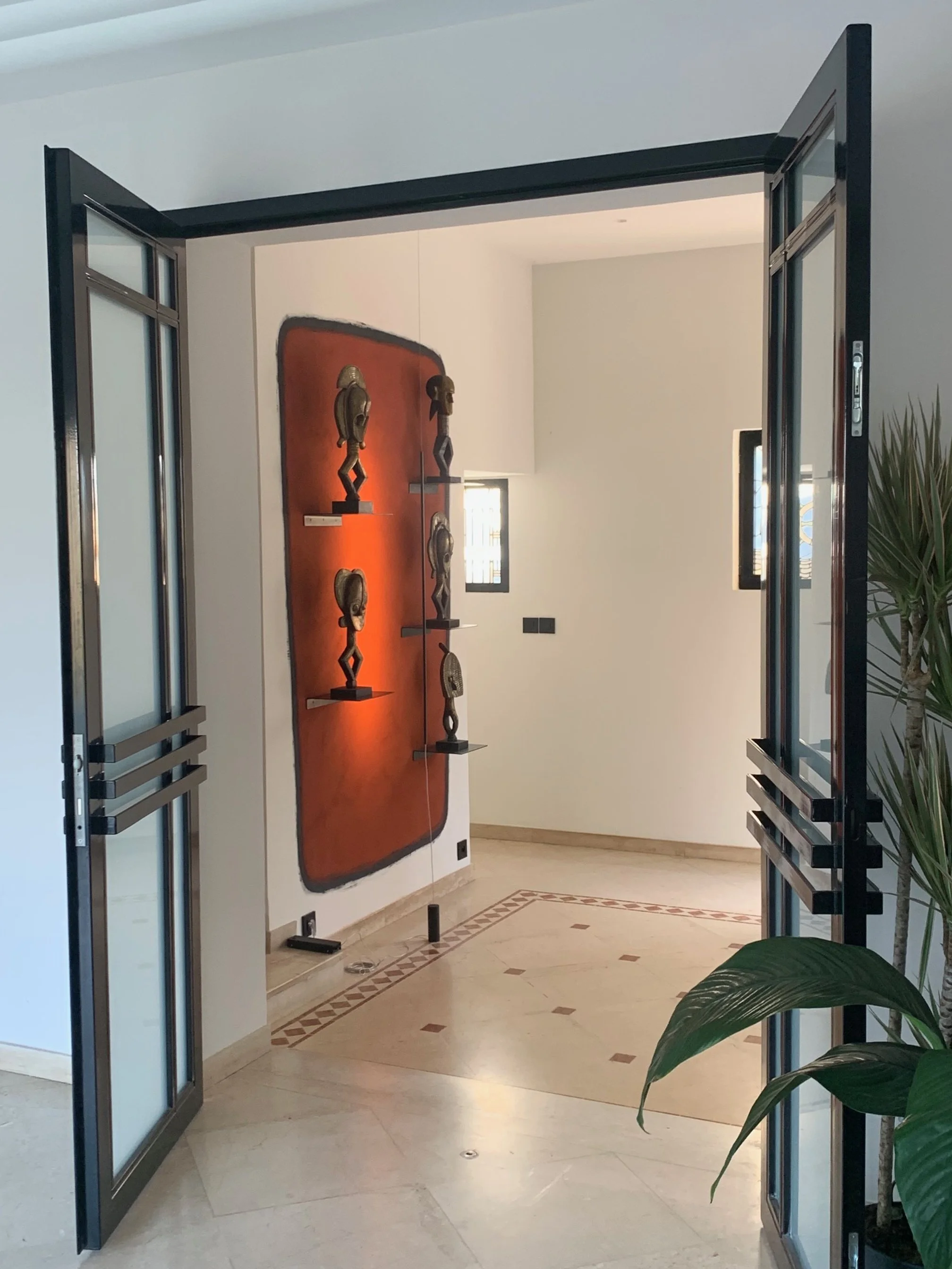 Entrance hall seen through steel and glass doors with a lacquered orange door