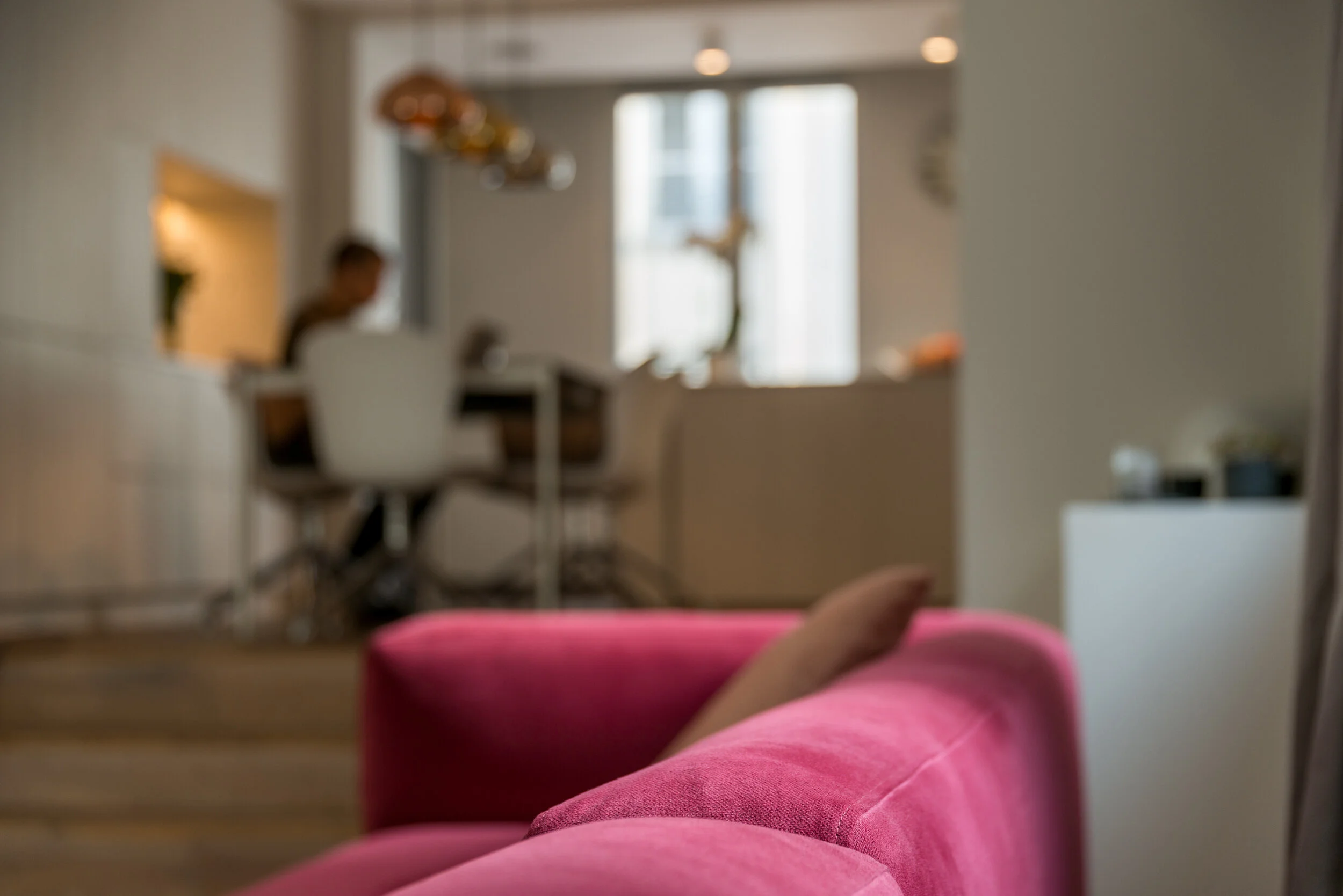 Living room with a pink sofa and the open kitchen beyond