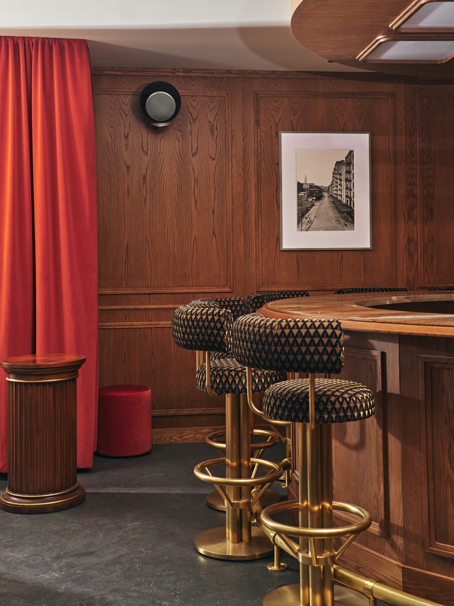 Le Chêne oak-panelled bar with brass stools and red curtain