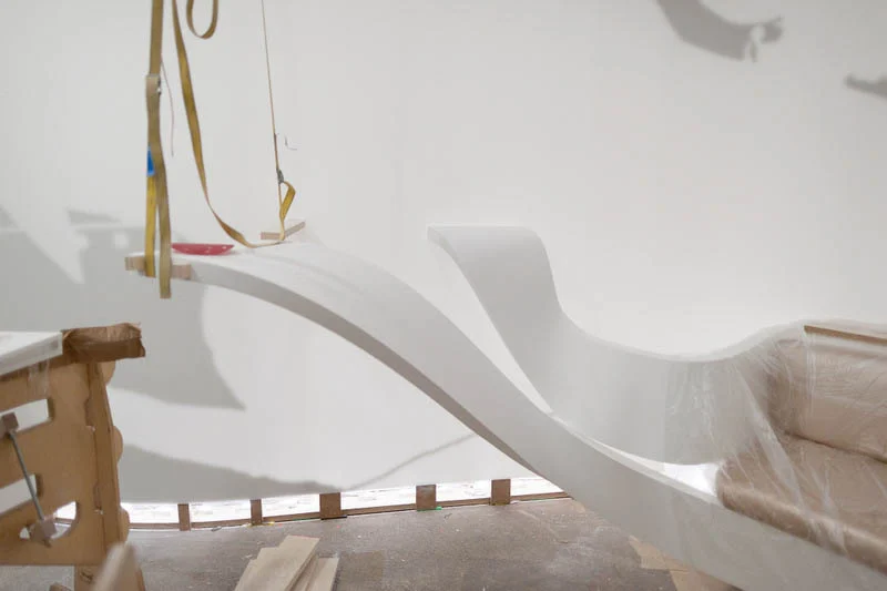 Sculptural white bench mid-installation in the workshop