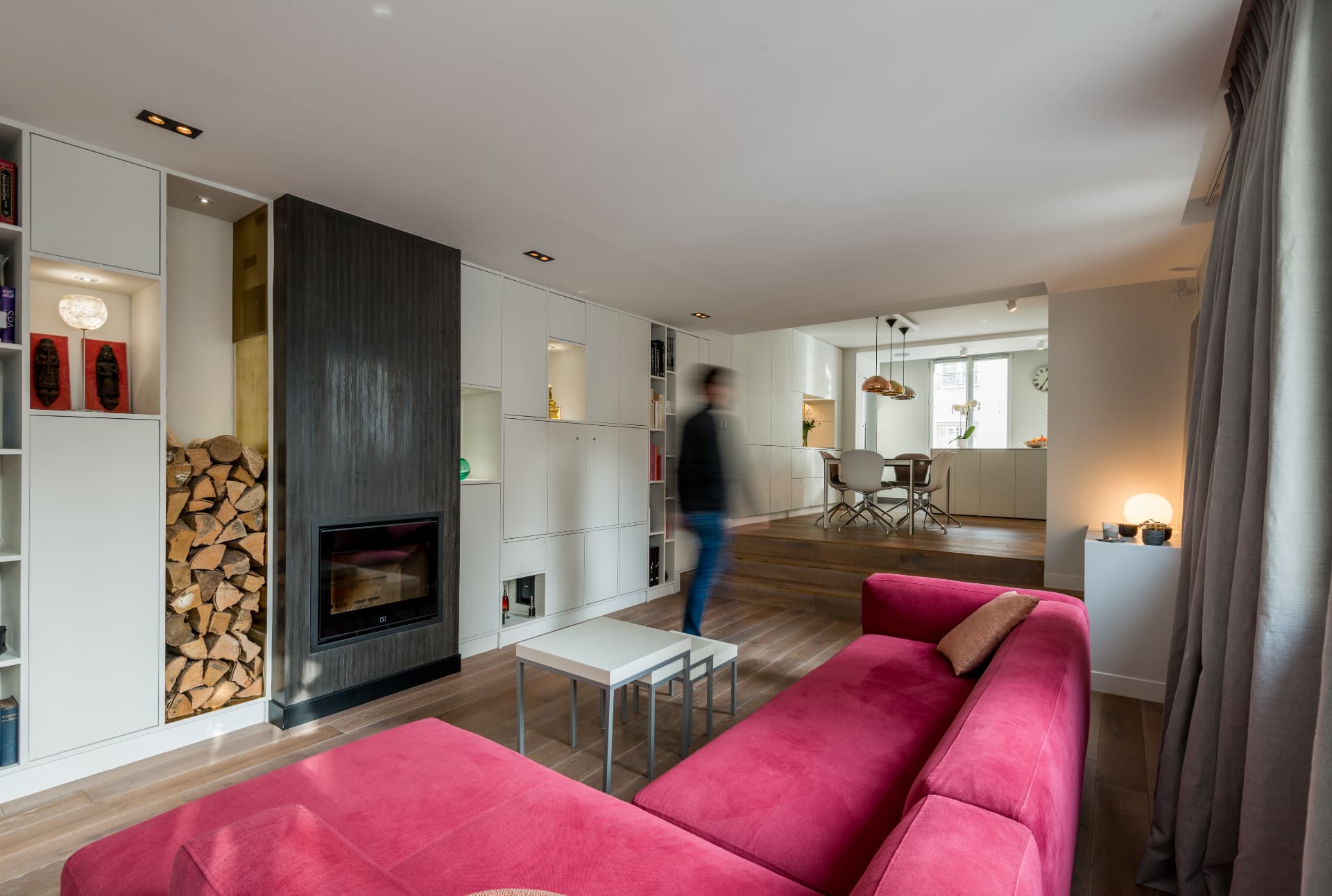 Living room with raspberry sectional and stacked firewood niche